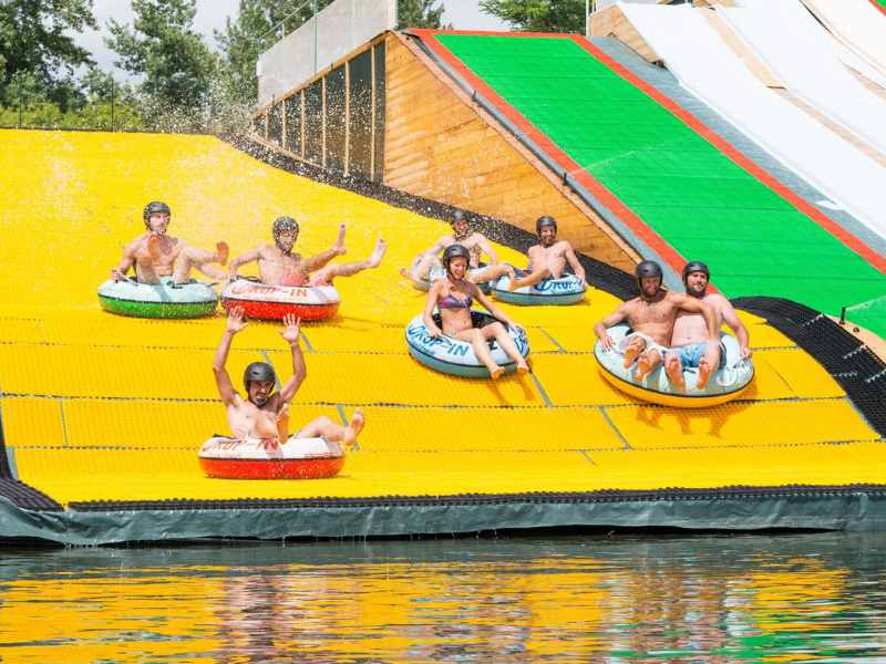 Une groupe de personnes descend un toboggan Water Jump à bord de bouées près de Lourdes